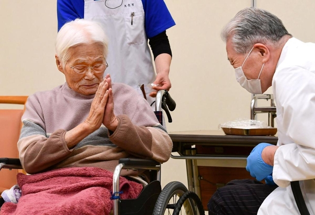 ワクチン接種を受け終わり、医師に手を合わせて感謝する高齢者（左）＝１２日午後０時５分、伊丹市中央４（撮影・秋山亮太）