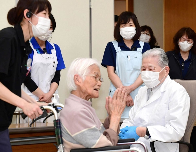 ワクチン接種を受け笑顔で会場を去る高齢者（中央）をほほえみ見送る医師ら＝１２日午後０時５分、伊丹市中央４（撮影・秋山亮太）