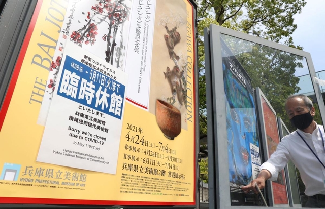 緊急事態宣言に伴う臨時休館の告知を掲示する兵庫県立美術館の職員＝２４日午後、神戸市中央区脇浜海岸通１（撮影・吉田敦史）