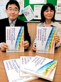 不妊手術を受けさせられた原告らの訴えが詰まった本を持つ支援者＝神戸市中央区橘通１