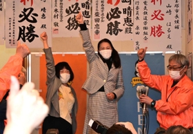 当選を決め支援者らと親指を立てて喜ぶ山崎晴恵氏（中央）＝１１日夜、宝塚市小林５（撮影・秋山亮太）