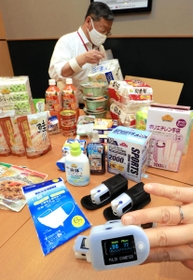 酸素濃度を測定できるパルスオキシメーター（手前）の貸与品や食料品など自宅療養者向けに配送される支援物資＝１３日午後、神戸市兵庫区中之島２、イオンモール神戸南（撮影・小林良多）