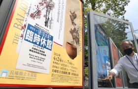 緊急事態宣言に伴う臨時休館の告知を掲示する兵庫県立美術館の職員＝２４日午後、神戸市中央区脇浜海岸通１（撮影・吉田敦史）