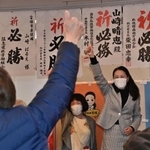 当選を決め支援者らと親指を立てて喜ぶ山崎晴恵氏（右）＝１１日夜、宝塚市小林５（撮影・秋山亮太）