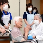 ワクチン接種を受け笑顔で会場を去る高齢者（中央）をほほえみ見送る医師ら＝１２日午後０時５分、伊丹市中央４（撮影・秋山亮太）