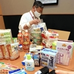 酸素濃度を測定できるパルスオキシメーター（手前）の貸与品や食料品など自宅療養者向けに配送される支援物資＝１３日午後、神戸市兵庫区中之島２、イオンモール神戸南（撮影・小林良多）