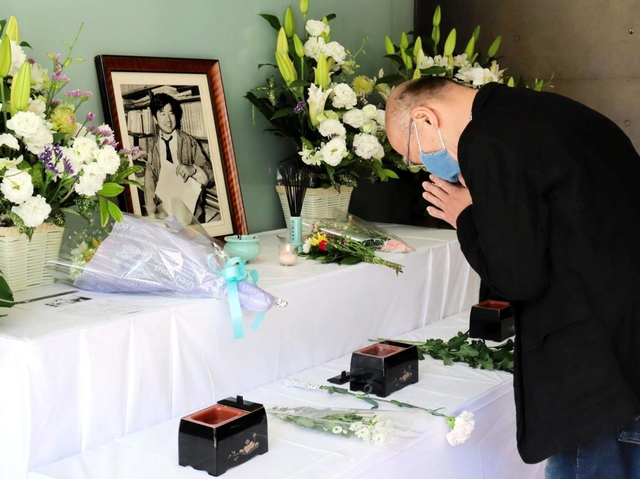 小尻記者の遺影が飾られた祭壇で手を合わせる男性＝西宮市与古道町