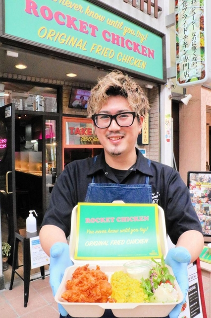 ロケットチキン神戸店の前で、商品を手にする武内謙二店長＝神戸市中央区元町通５