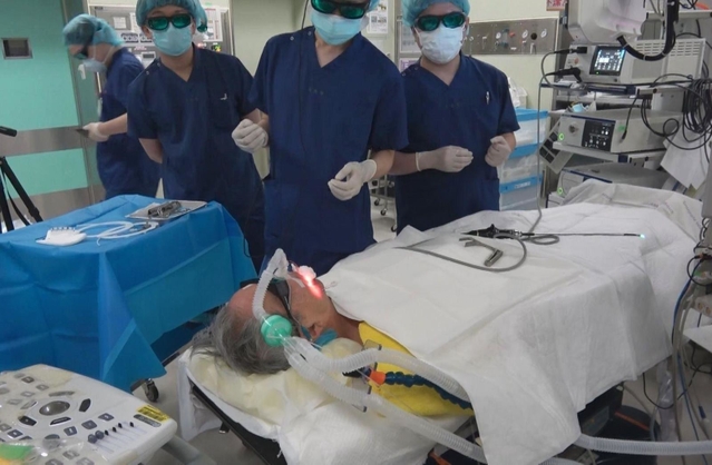 サングラスのような特殊な眼鏡をかけて照射を見守るスタッフ＝４月２３日、神戸市中央区楠町７、神戸大病院（神戸大学・神戸新聞共同撮影）