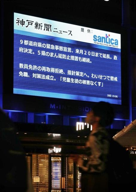 緊急事態宣言の延長の政府決定を伝えるニュース＝２８日夜、神戸市中央区雲井通７（撮影・長嶺麻子）