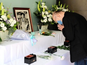 小尻記者の遺影が飾られた祭壇で手を合わせる男性＝西宮市与古道町