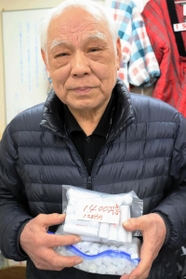 １円玉の束を抱える花崎治良さん＝神戸市兵庫区東山町１