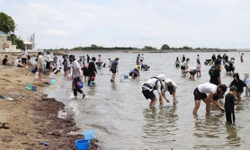 営業を再開した潮干狩り場で貝を探すマスク姿の親子連れら＝１５日午前、たつの市御津町黒崎