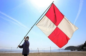 津波発生を想定して旗を振る女性＝たつの市御津町黒崎