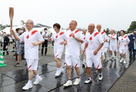聖火リレー２日目の第一走者を務めた「５６年目のファーストランの会」のメンバー＝２４日午後、丹波篠山市北新町、篠山城跡三の丸広場（撮影・長嶺麻子）