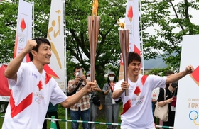 トーチキス後にポーズを決める朝原宣治さん（左）と武井壮さん＝２４日午後、丹波篠山市北新町、篠山城跡三の丸広場（撮影・中西幸大）