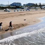 潮干狩りの営業を休止している砂浜を清掃するスタッフ＝３日午前、姫路市的形