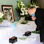 小尻記者の遺影が飾られた祭壇で手を合わせる男性＝西宮市与古道町