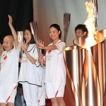 聖火を囲んで笑顔で手を振る聖火リレーのランナーたち。中央は北京五輪５千メートル代表の小林祐梨子さん＝２３日午後、姫路市本町（撮影・小林良多）