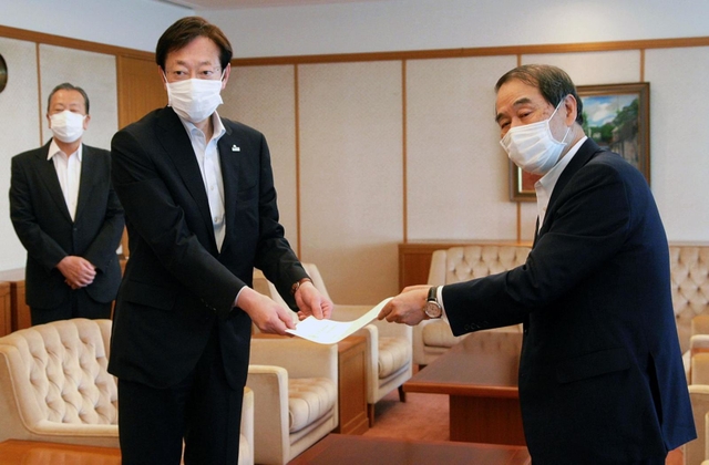 家次恒・日本商工連盟神戸地区代表から立候補要請書を受け取った久元喜造神戸市長（左）＝神戸市役所