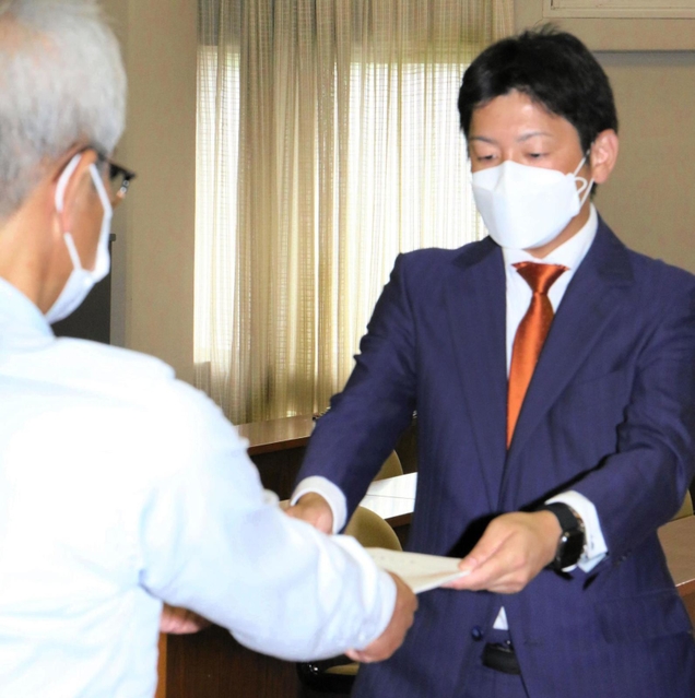 尼崎市議選で投票の数え直しなどを求め異議申立書を手渡す次点の寺坂美一氏（右）＝尼崎市役所