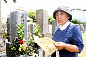 長男・雅生さんの墓前で、最終号の「風通信」を手にする曽我部とし子さん＝明石市内