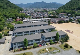 モダンな外観が山あいに映える西脇小学校の木造校舎３棟（小型無人機で撮影）＝西脇市西脇（撮影・大森　武）