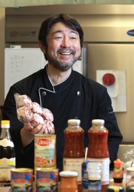 本山尚義さん。手には「見た目は白子っぽいが弾力がある」という羊の脳みそ。工房の冷蔵庫には、ピラルクの切り身、カンガルーの肉なども＝神戸市東灘区（撮影・小林良多）