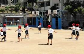 マスクを外した体育の授業。両手を広げて回る運動を取り入れるなど、学校現場では間隔を空ける工夫をしている＝神戸市垂水区美山台２、乙木小学校