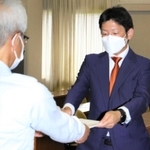 尼崎市議選で投票の数え直しなどを求め異議申立書を手渡す次点の寺坂美一氏（右）＝尼崎市役所