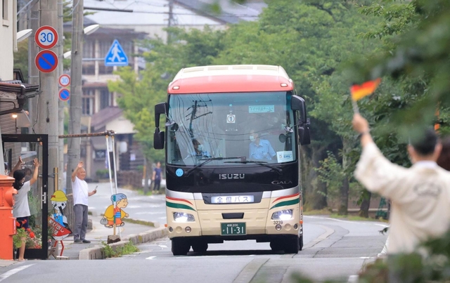 城崎温泉に到着し、住民らに歓迎されるボートのドイツ選手団を乗せたバス＝２日午後、豊岡市城崎町湯島