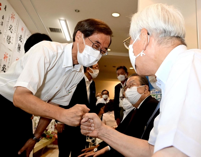井戸敏三知事に「グータッチ」であいさつする金沢和夫氏（左）＝１８日午後８時３２分、神戸市中央区元町通１（撮影・中西幸大）