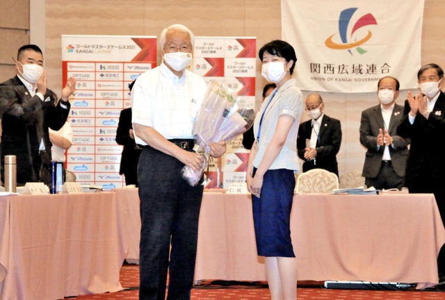 関西広域連合本部事務局の職員から花束を手渡され、笑顔を見せる井戸敏三知事（左から２人目）＝29日午前、大阪市北区