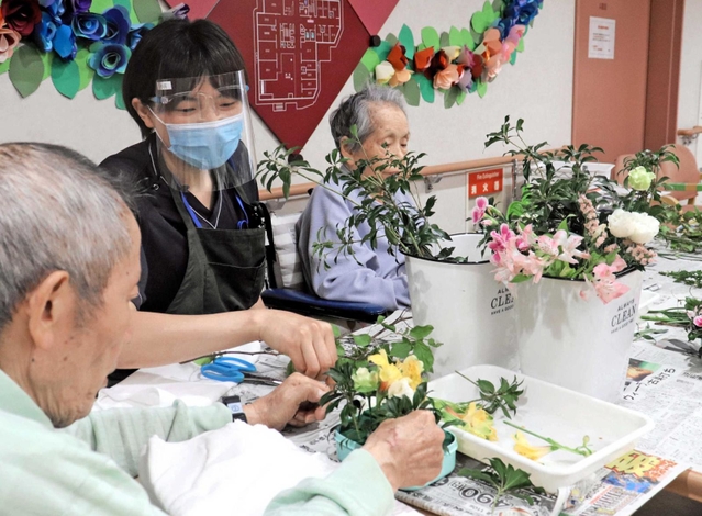 園芸療法士の助言を受けてフラワーアレンジメントに取り組む高齢者＝東京都荒川区、介護老人保健施設「ひぐらしの里」