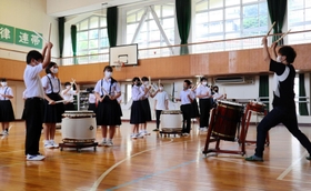 山中裕貴さん（右）の指導で和太鼓に触れる生徒ら＝神戸市中央区熊内町６、市立布引中学校