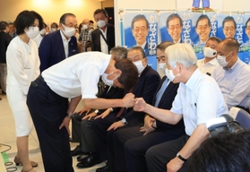井戸敏三知事（右）に頭を下げながらグータッチする金沢和夫氏＝１８日午後８時３２分、神戸市中央区元町通１（撮影・鈴木雅之）