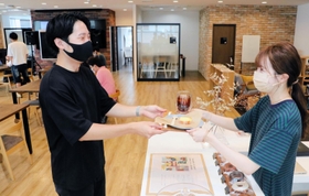 ３周年を記念し、無料で提供された菓子や飲料を受け取る利用者＝神戸市中央区磯上通４、１２０ＷＯＲＫＰＬＡＣＥ　ＫＯＢＥ