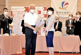 関西広域連合本部事務局の職員から花束を手渡され、笑顔を見せる井戸敏三知事（左から２人目）＝29日午前、大阪市北区