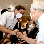 井戸敏三知事に「グータッチ」であいさつする金沢和夫氏（左）＝１８日午後８時３２分、神戸市中央区元町通１（撮影・中西幸大）