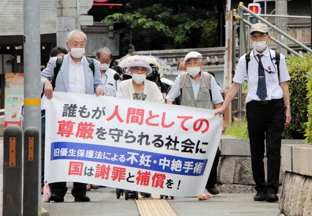 横断幕を手に神戸地裁に入場する強制不妊訴訟の原告団たち＝３日午後０時４８分、神戸市中央区橘通２