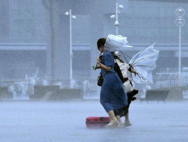 強い風と雨で、傘がひっくり返った女性たち。台風９号の影響で、神戸市にも暴風・波浪警報が出され、断続的に風雨が強まった＝９日午前１１時３４分、神戸市中央区波止場町（撮影・鈴木雅之）