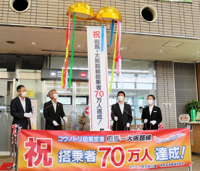 ７０万人達成を祝い、くす玉を割る関係者たち＝豊岡市岩井