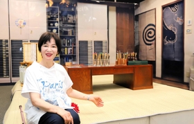 仕事場を再現した展示空間を紹介する尼子騒兵衛さん。実際に使った机や画材道具が並ぶ＝尼崎市昭和通２、尼崎市総合文化センター