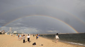 突然の雨とともに砂浜の向こうに架かった巨大な二重の虹＝６日午後、神戸市須磨区須磨浦通４（撮影・小林良多）