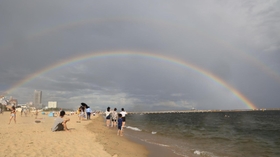 突然の雨とともに砂浜の向こうに架かった巨大な二重の虹＝６日午後、神戸市須磨区須磨浦通４（撮影・小林良多）