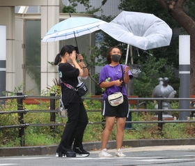 強い風にあおられる人たち＝９日午前１１時５３分、神戸市中央区東川崎町１（撮影・吉田敦史）
