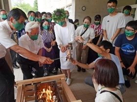 芦屋市立精道小学校で開かれた採火式。市民から募ったメッセージの紙などを燃やした火がランタンに移された＝１２日午後、芦屋市精道町（撮影・秋山亮太）