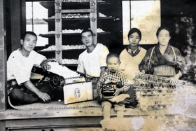 中国で戦没した父親の輝治さん（左から２人目）らと撮った家族の写真。幼い頃の柿原啓志さん（中央）は父がお土産でくれた獅子舞の頭を持つ（柿原さん提供）