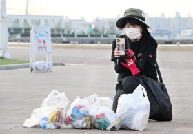 拾ったごみを撮影して投稿する内波知子さん＝神戸市中央区波止場町