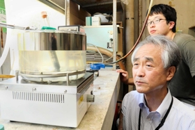 アンモニア化合物の水溶液から水素を取り出す実験を見守る森下政夫教授（手前）＝姫路市書写、兵庫県立大